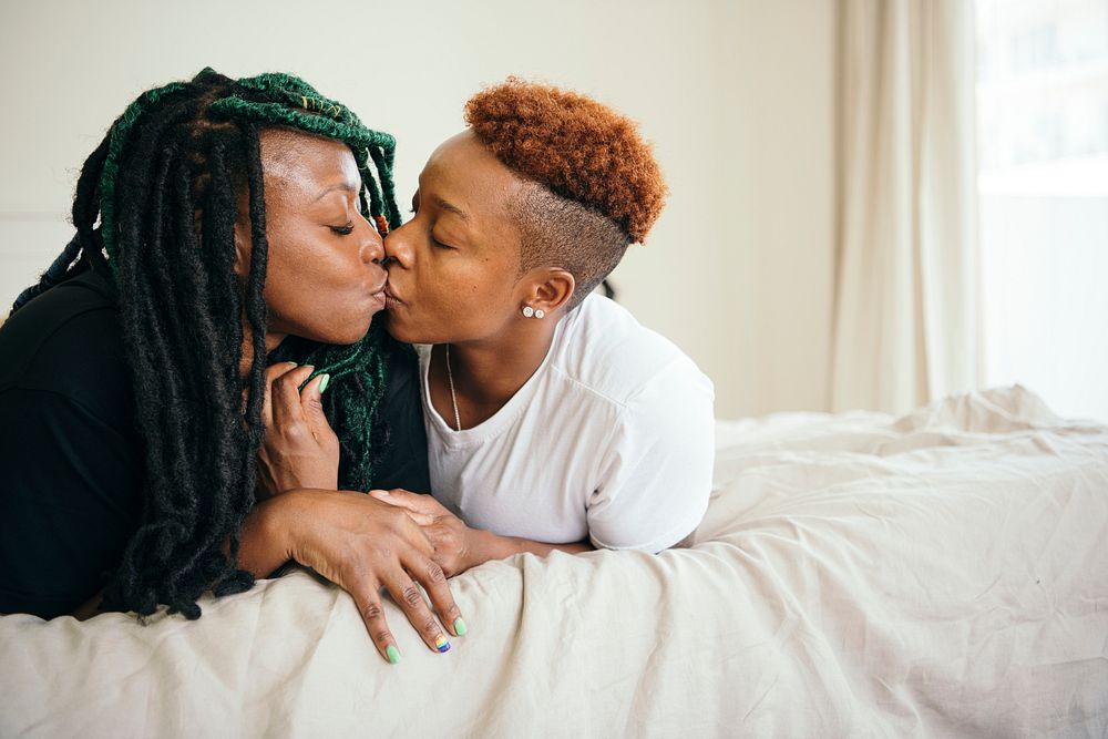 Happy lesbian couple smooching in bed