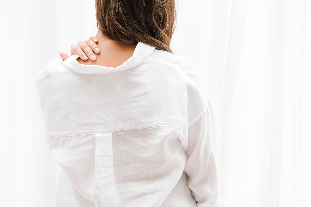 Woman in a white linen shirt touching her neck