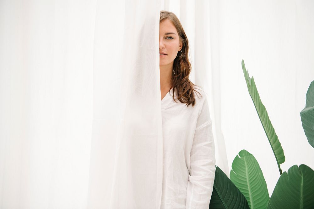 Woman hiding behind a white curtain