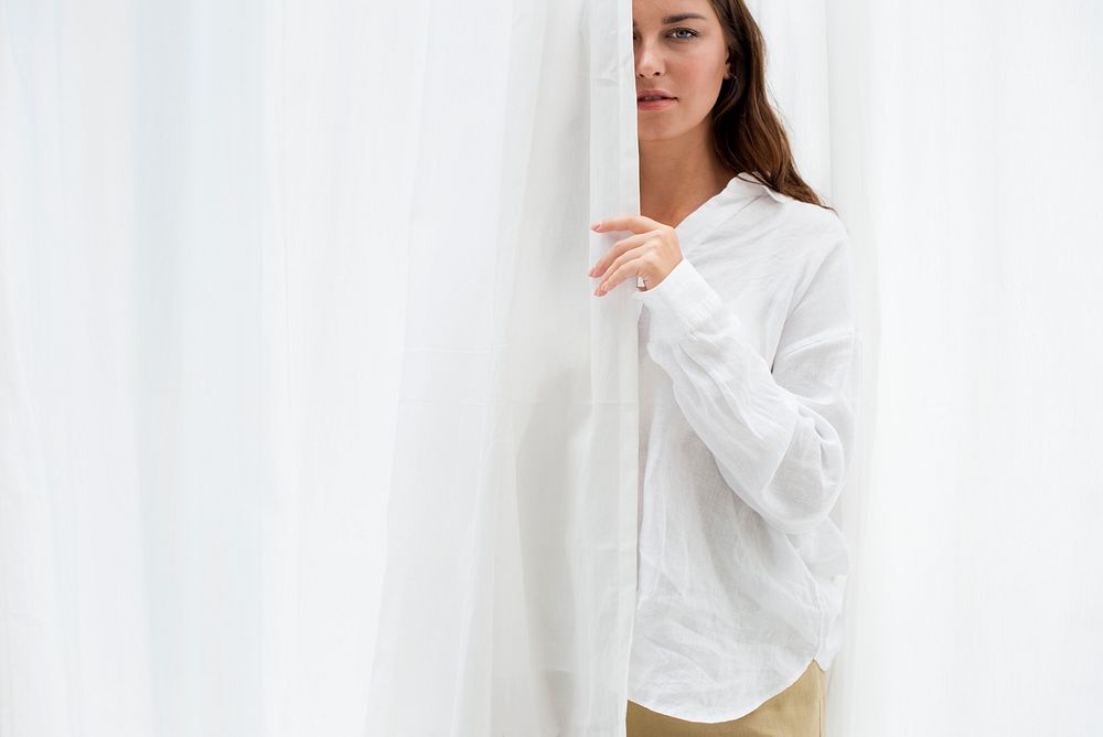 Woman hiding behind a white curtain