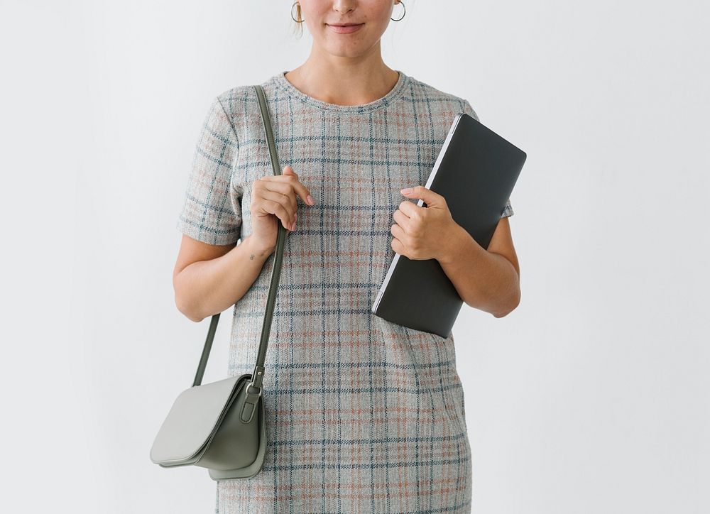 Woman in a gray plaid dress holding a laptop