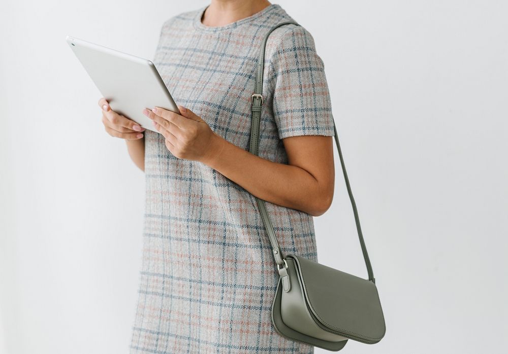 Woman in a gray plaid dress using a tablet