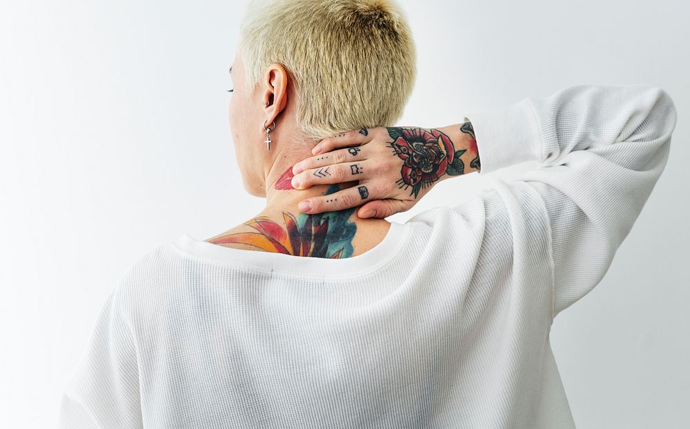 Rearview of a tattooed woman touch her neck