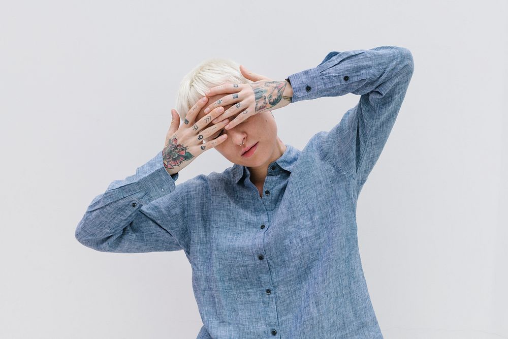 Woman wearing a blue shirt standing against a white wall