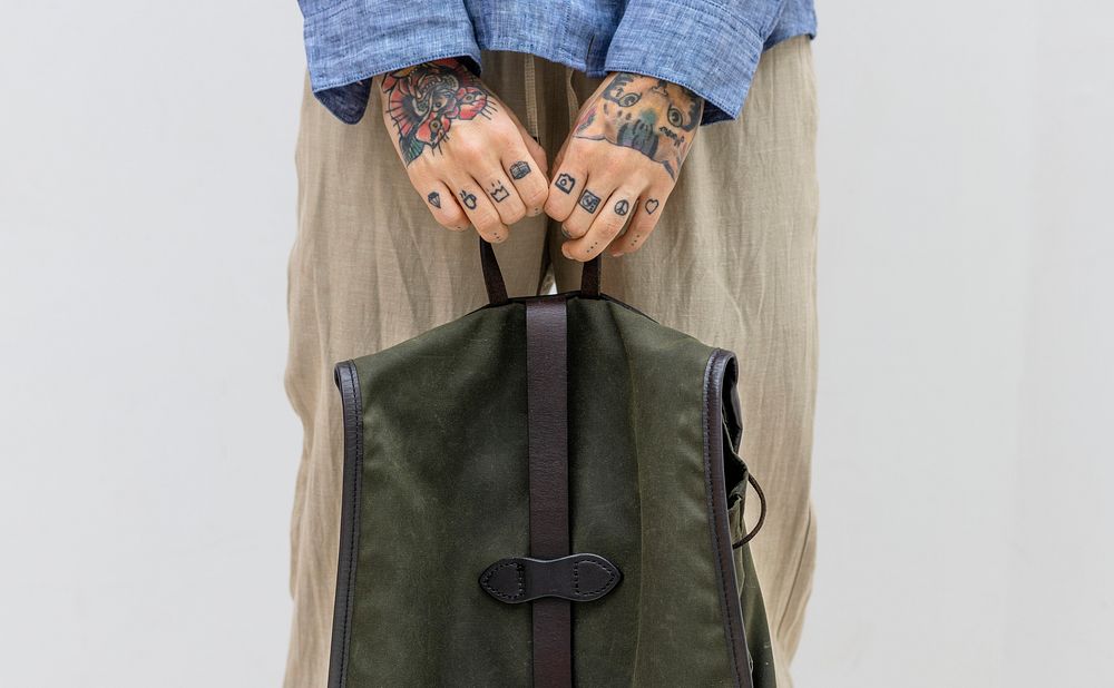 Tattooed hands holding a green bag