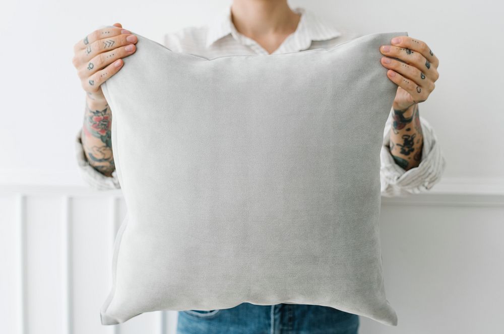 Tattooed woman holding a gray pillow