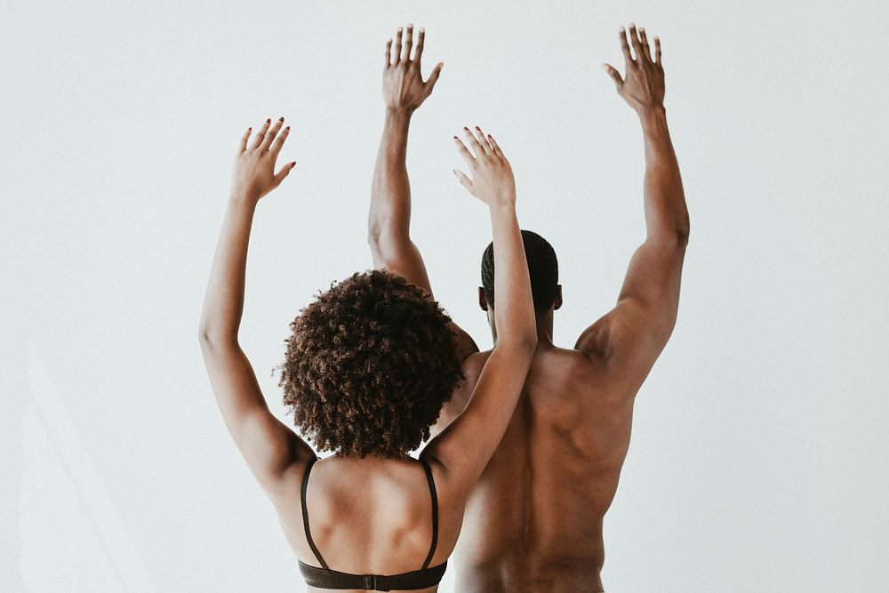 Seminude black couple raising arms in the air