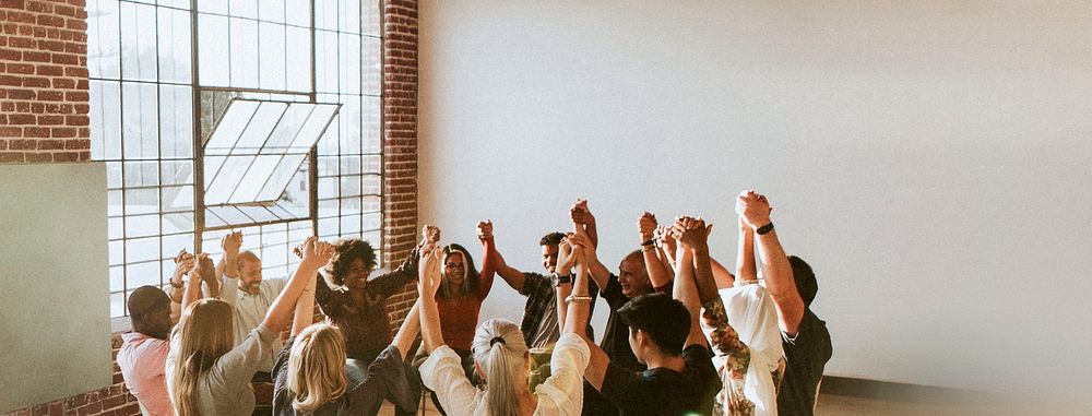 Group of diverse people holding hands up in the air