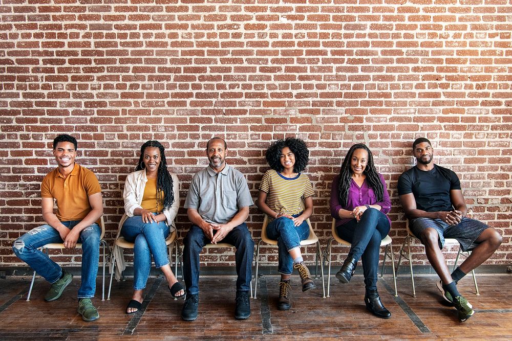 Diverse people sitting in a row against a brick wall background