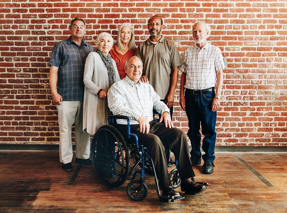 Happy elderly man on a wheelchair with friends