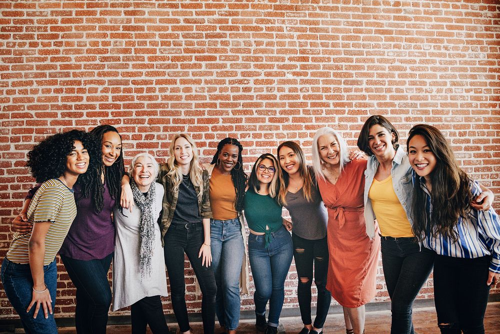 Cheerful diverse women standing in front of a red brick wall