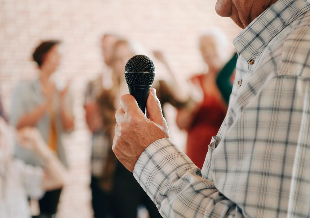 Elderly man speaking on a microphone in a seminar