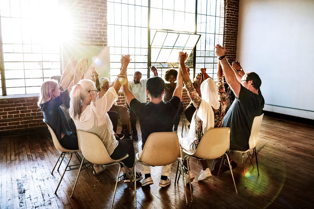 Group of diverse people holding hands up in the air