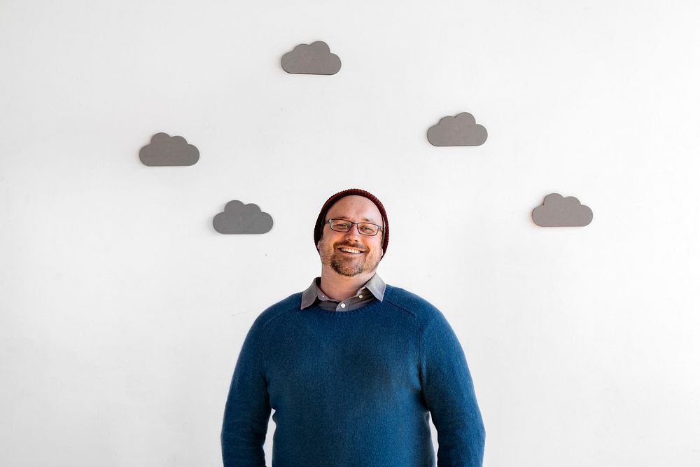 Cheerful man with decorated clouds on white wall