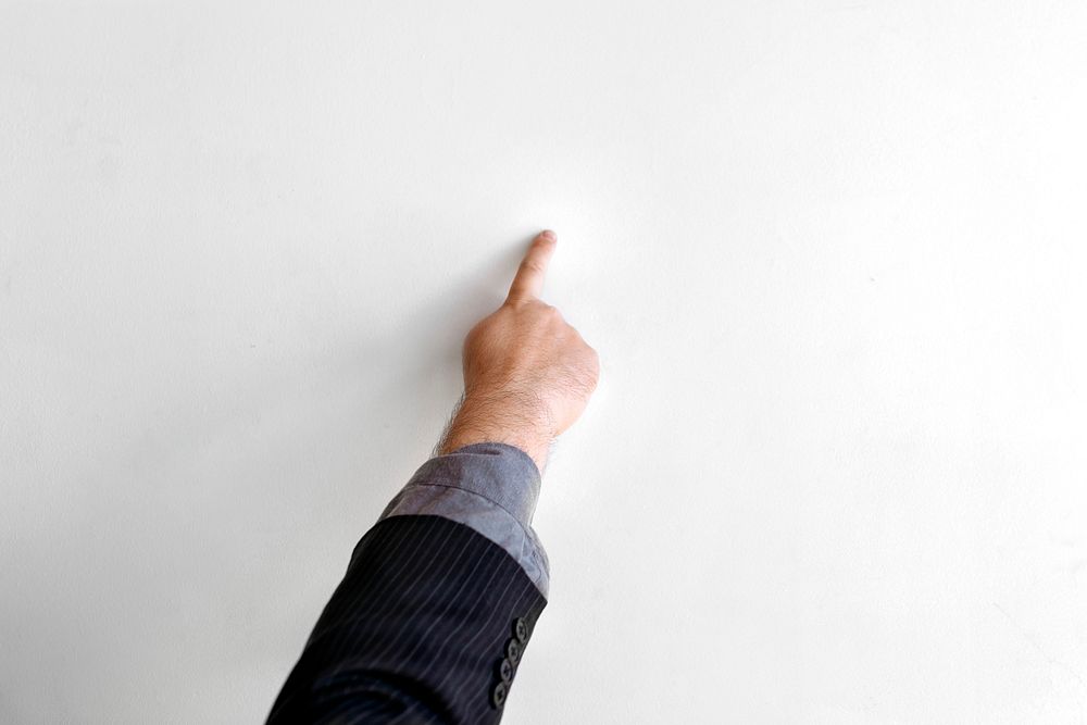 Hand pointing to a white wall