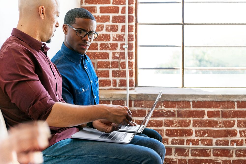 Two colleagues working together on their laptops