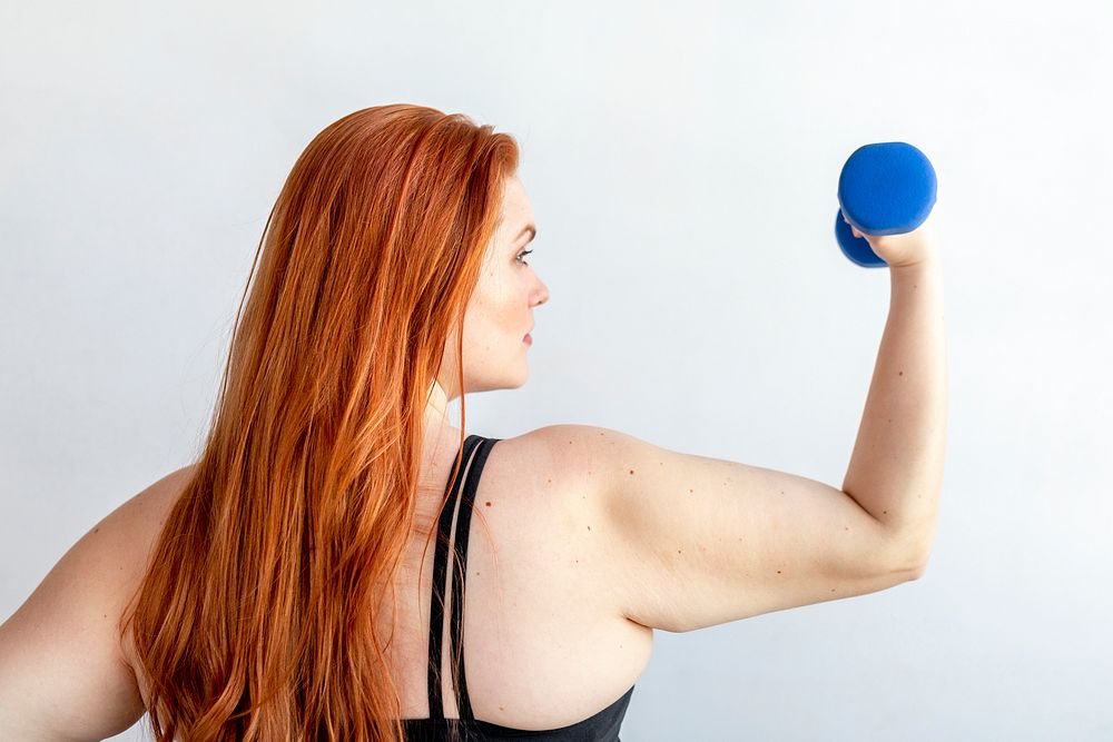 Rear view of active woman with dumbbell