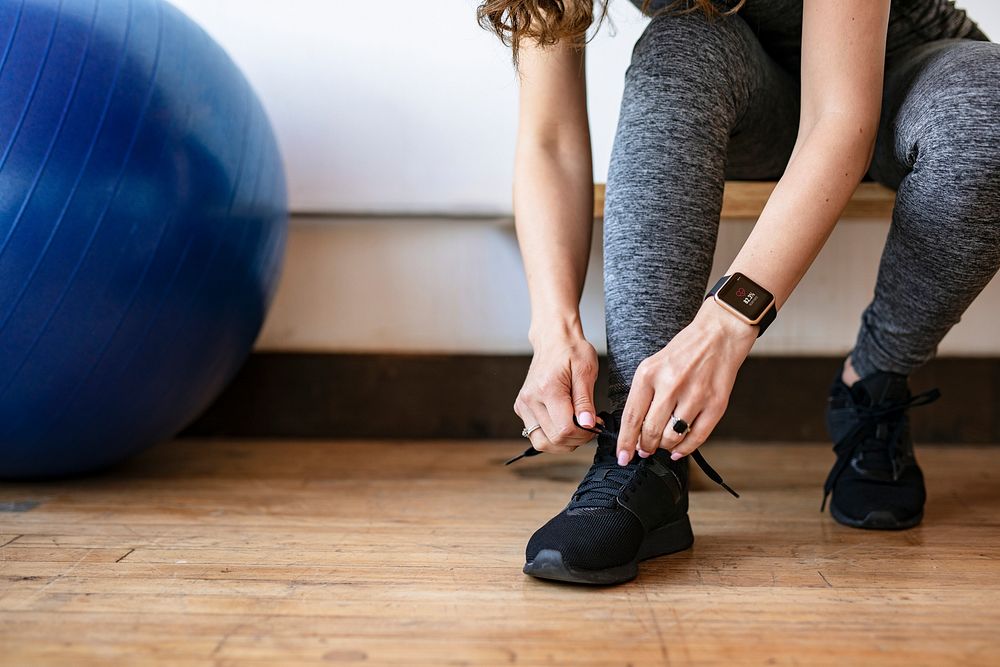 Active woman wearing a smartwatch tying her shoelaces