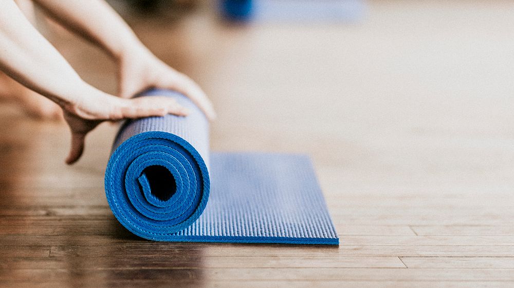 Yogi rolling her blue yoga mat