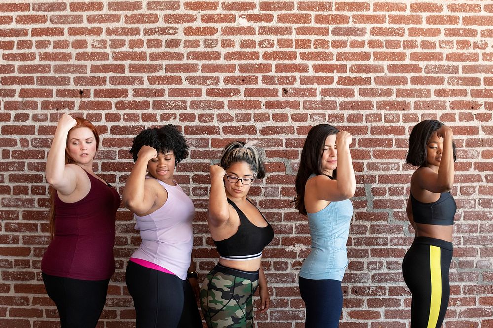 Group of sportive women standing by a brick wall