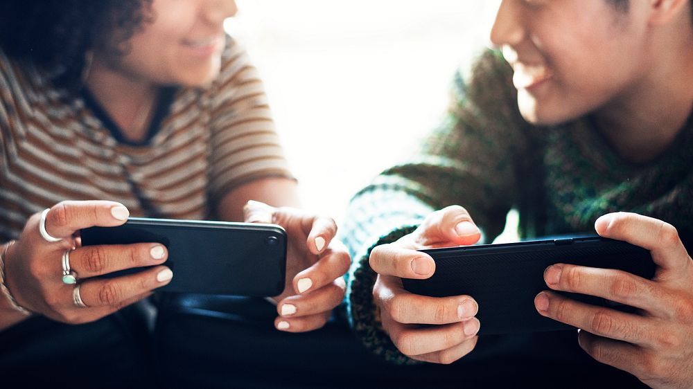 Cheerful couple playing online game on their phones wallpaper