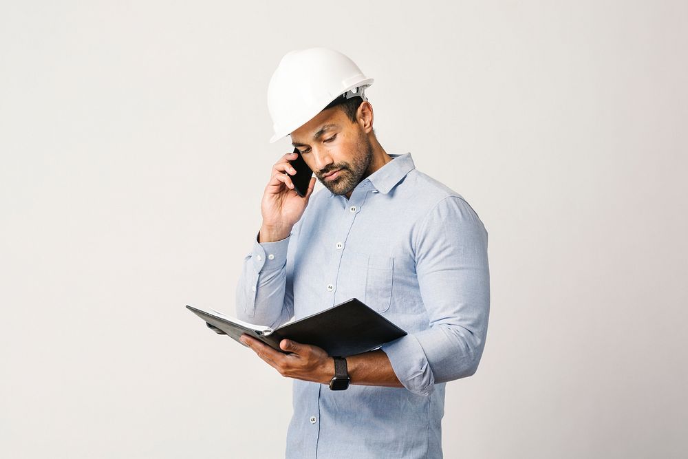 Engineer  checking on his planner while talking on the phone