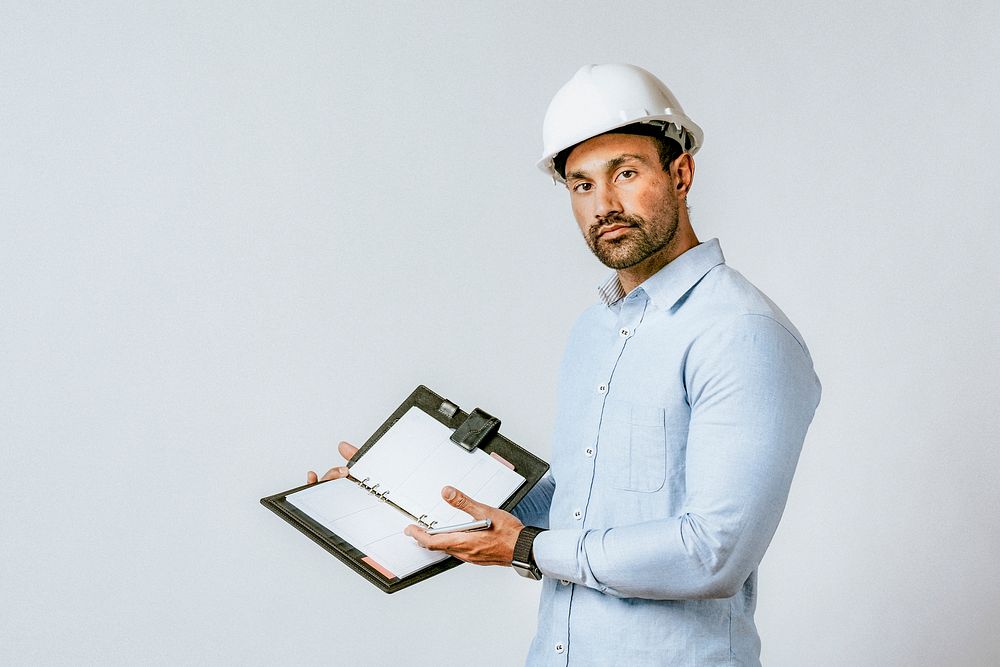 Engineer with a safety helmet showing his planner
