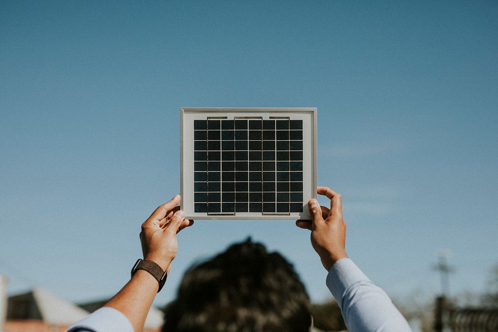 Rearview of eco-friendly woman holding a solar panel up in the sky