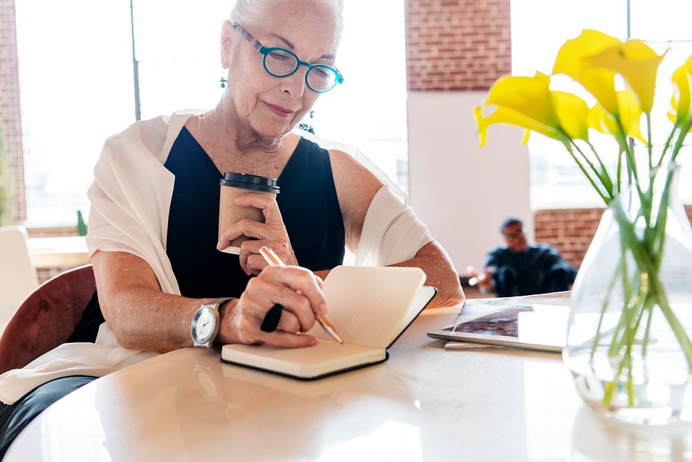 Mature woman writing a journal in her office