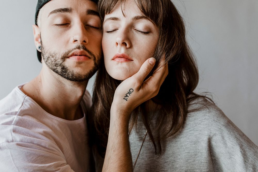 Man touching eyes-closed woman face