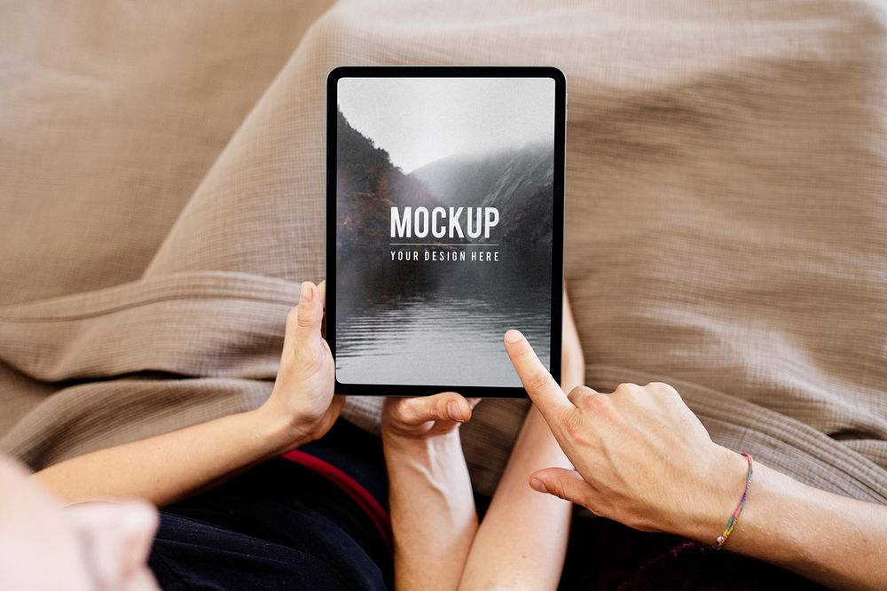 Couple using a tablet screen mockup together in bed