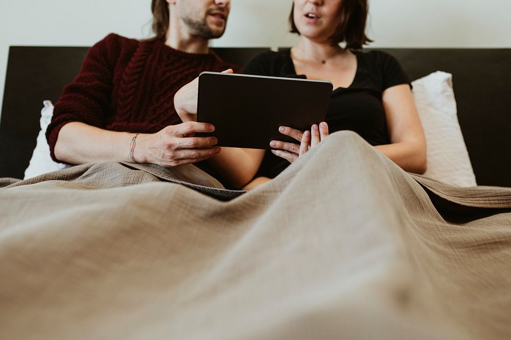 Husband and wife with a digital tablet in bed 