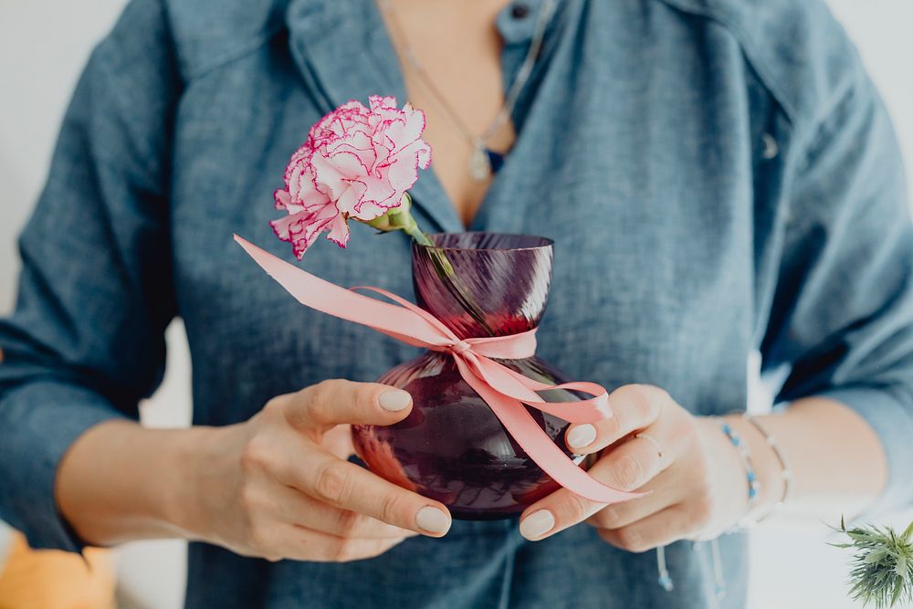 Woman holding a vase of a white pink carnation