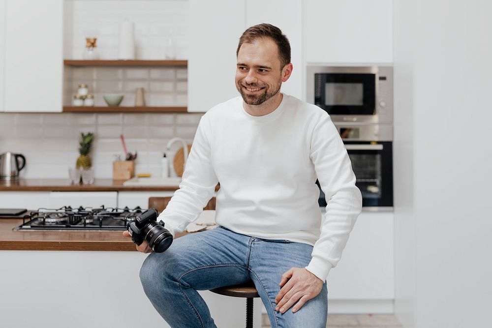 Cheerful man sitting on a stool with a camera