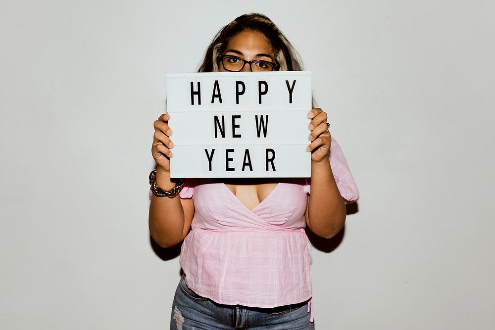 Woman with eyeglasses raising a happy new year board