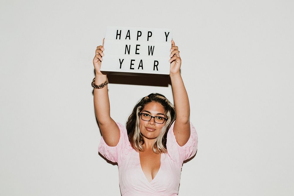 Woman with eyeglasses raising a happy new year board