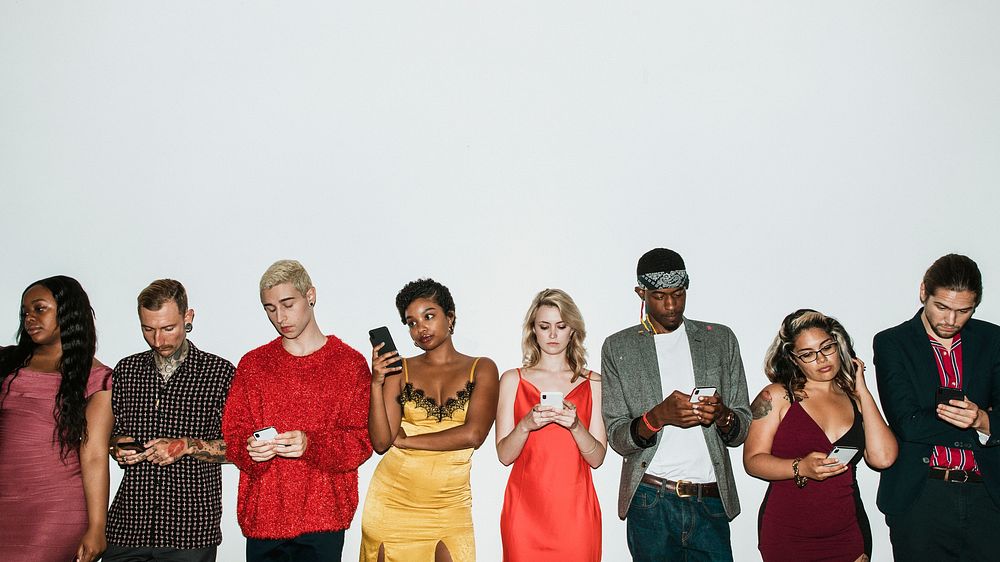 Diverse group of friends standing in a row using their smartphones