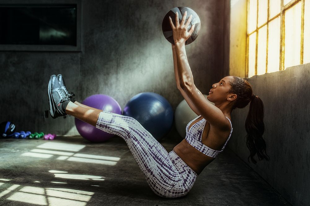 Woman weightlifting with a medicine ball in the gym