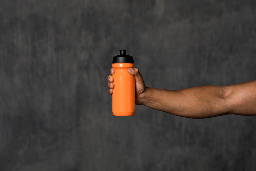 Muscular man holding an orange water bottle mockup