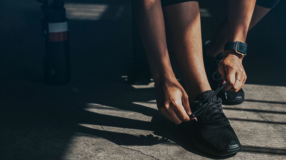 Woman tying her shoelaces, getting ready to exercise wallpaper