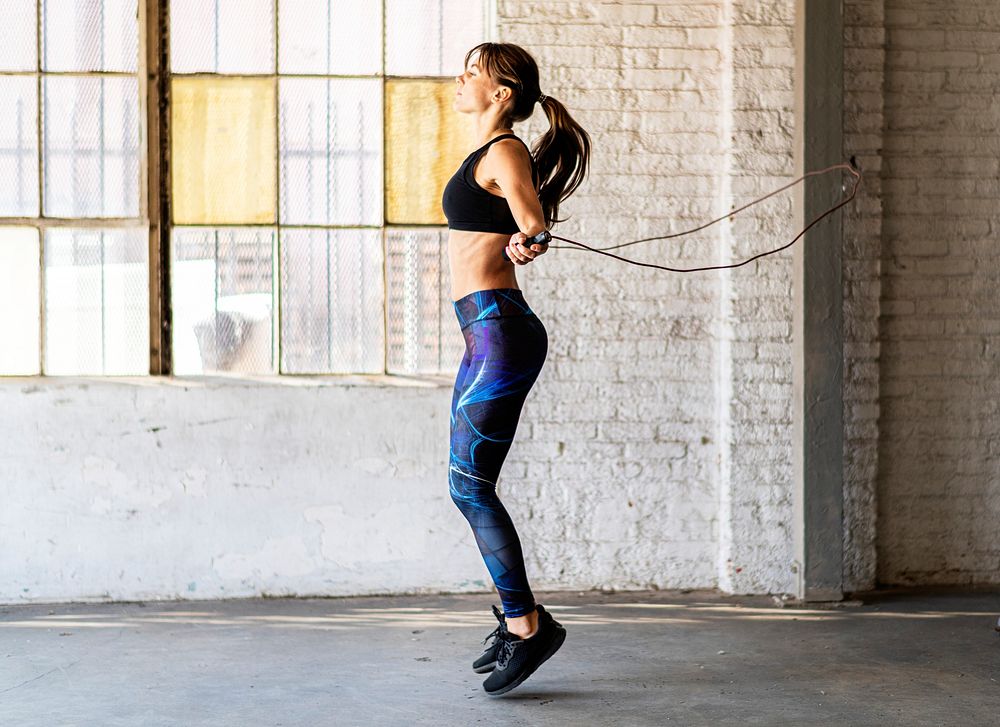 Sporty woman jumping skipping rope at gym