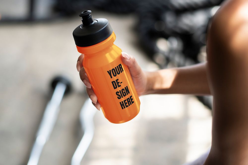 Muscular man holding an orange water bottle mockup