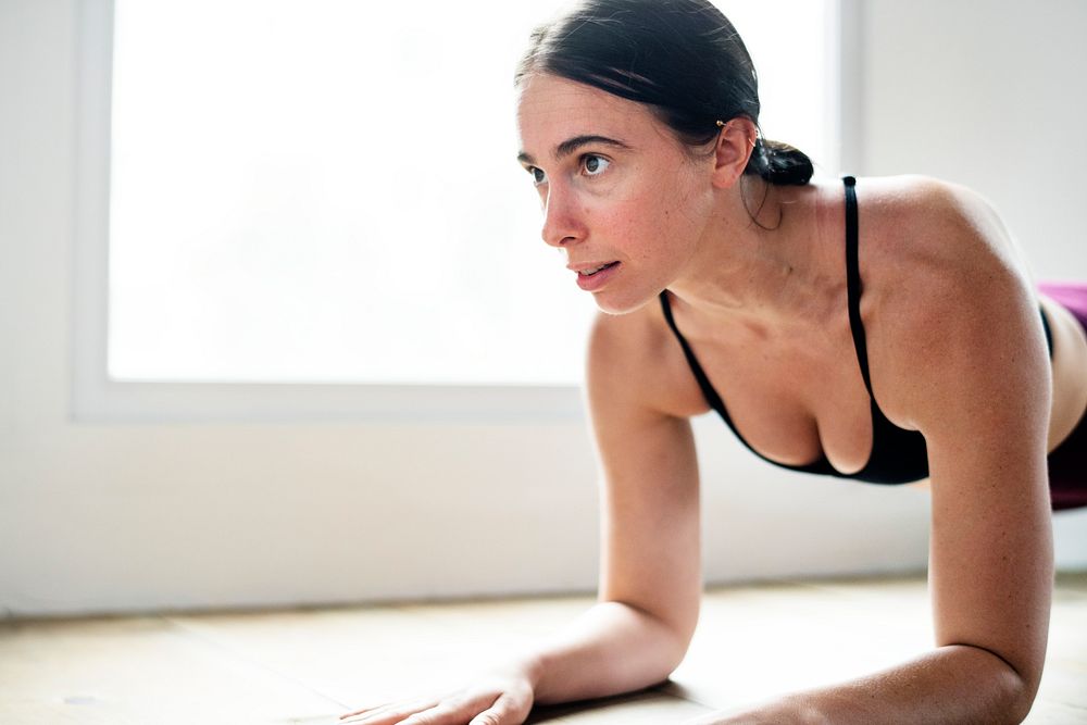 Sportive woman doing elbow plank on the floor