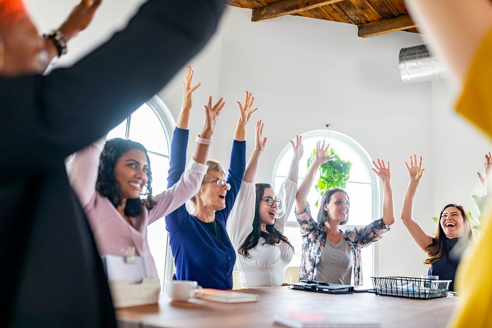 Happy women raising their arms in a meeting