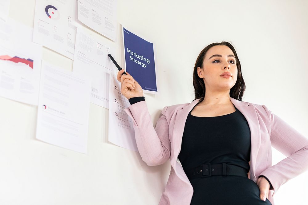 Businesswoman presenting a marketing strategy on a white wall