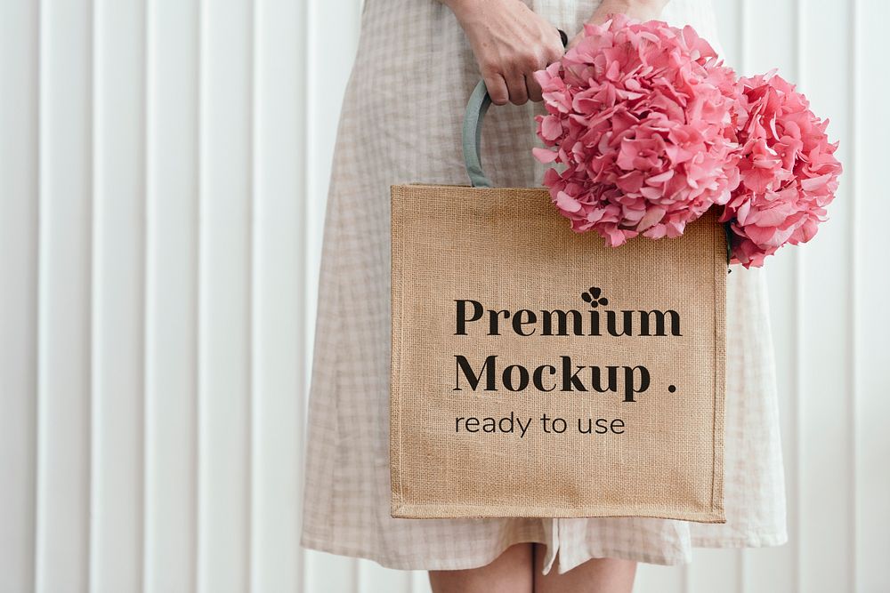 Woman holding a woven tote bag mockup with pink hydrangea