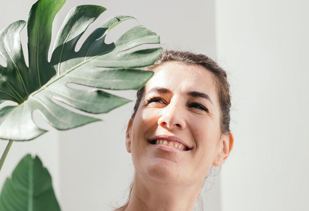 Cheerful woman with a split leaf philodendron