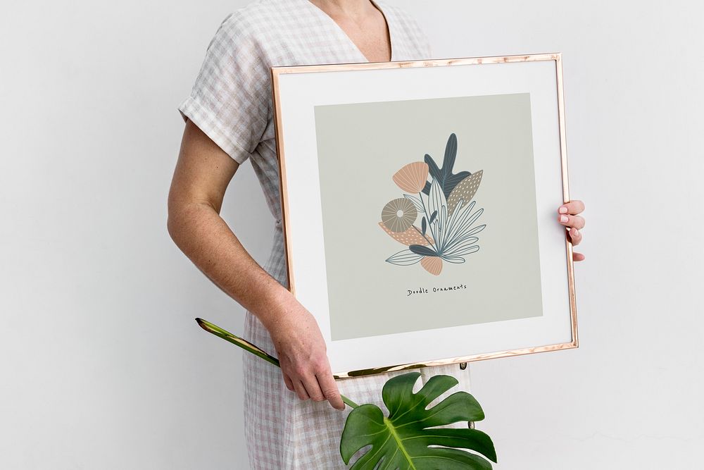 Woman holding a monstera leaf and a floral frame mockup