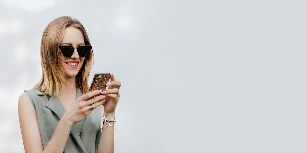 Happy woman playing on her phone outdoors