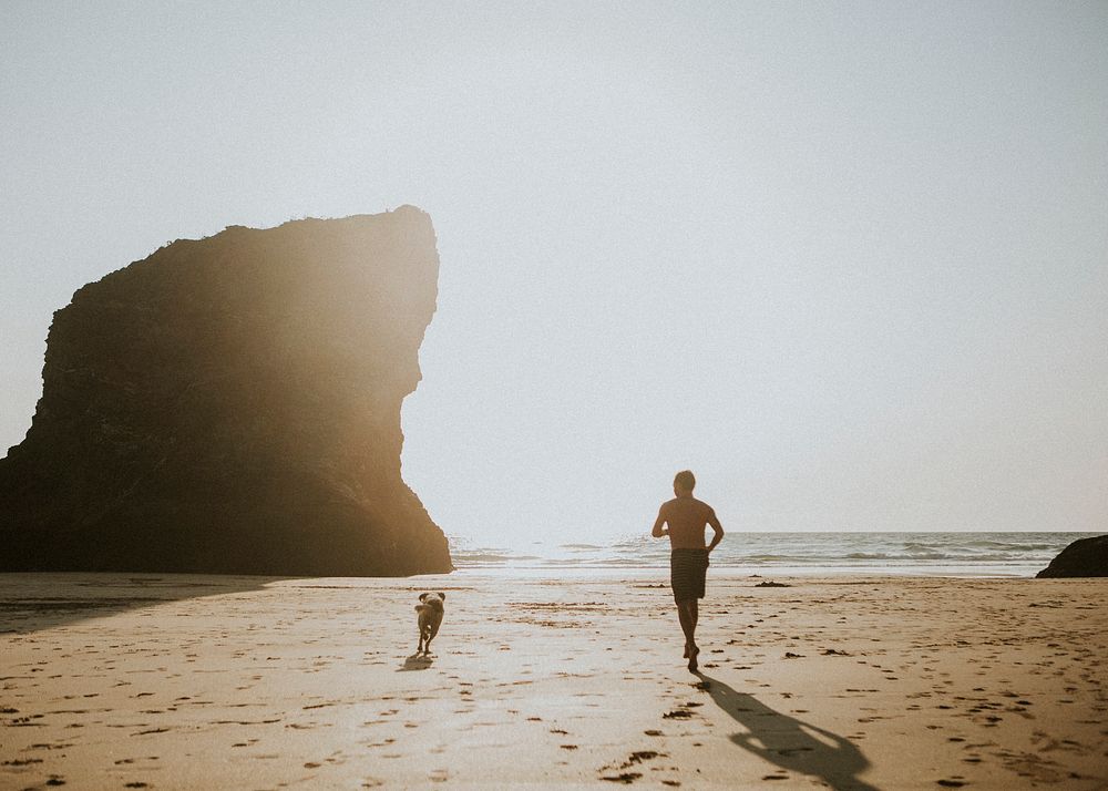 Man and a dog running on the beach